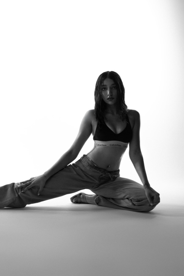 Black and white studio editorial — seated floor pose looking into camera