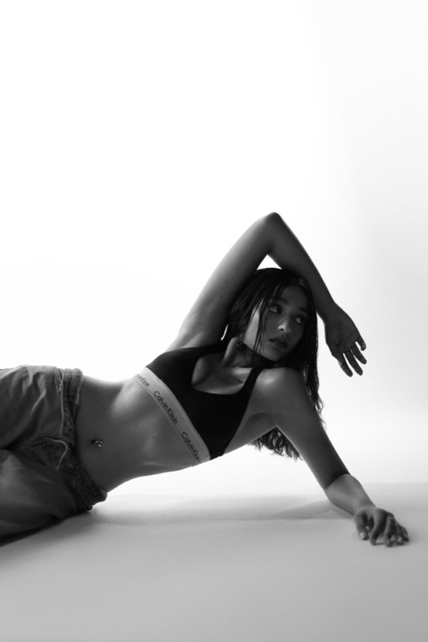 Black and white studio editorial — reclining with one arm arched overhead