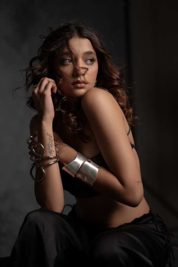 Moody studio fashion shot with stacked bracelets and a silver cuff
