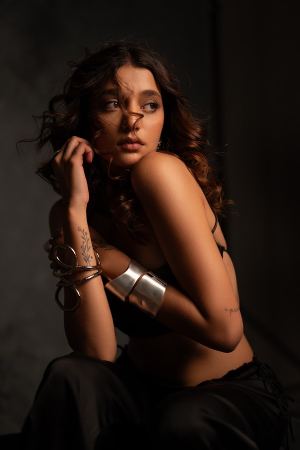 Moody studio fashion shot with a wide silver cuff, glancing away