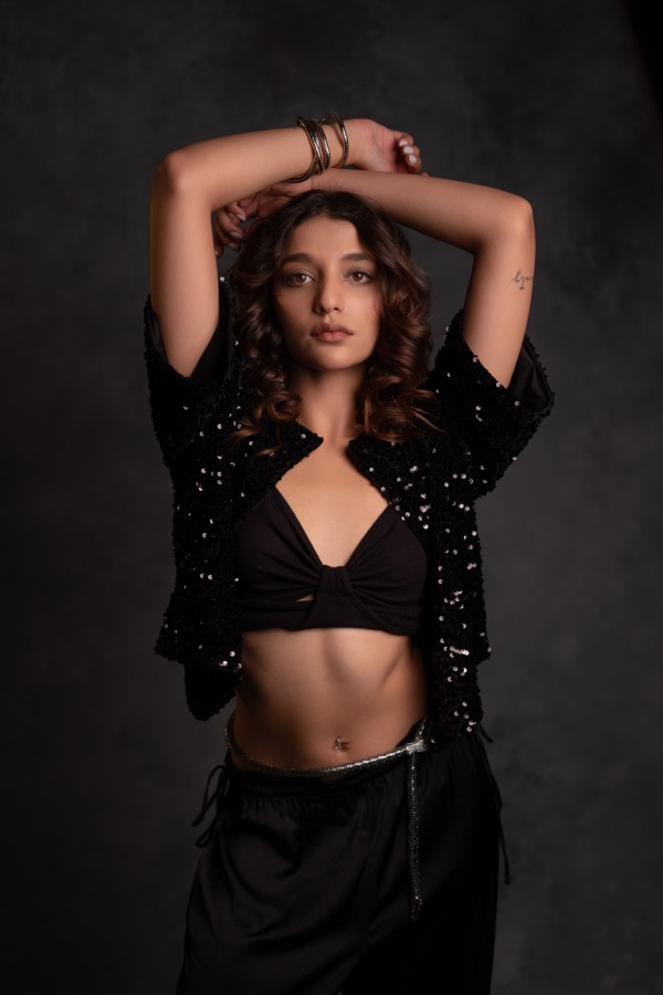 Studio fashion shot in a sequined jacket with arms raised overhead