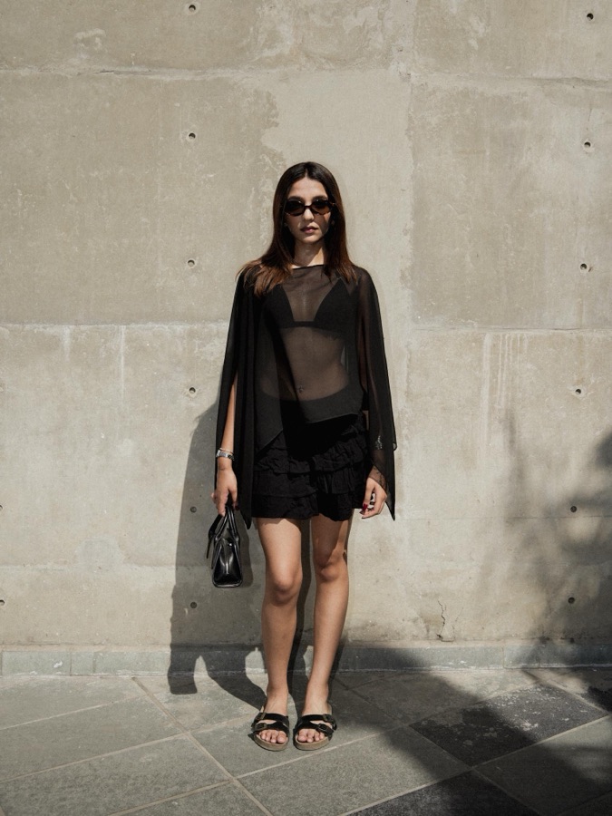 Street style look — sheer black layers with sunglasses against a stone wall