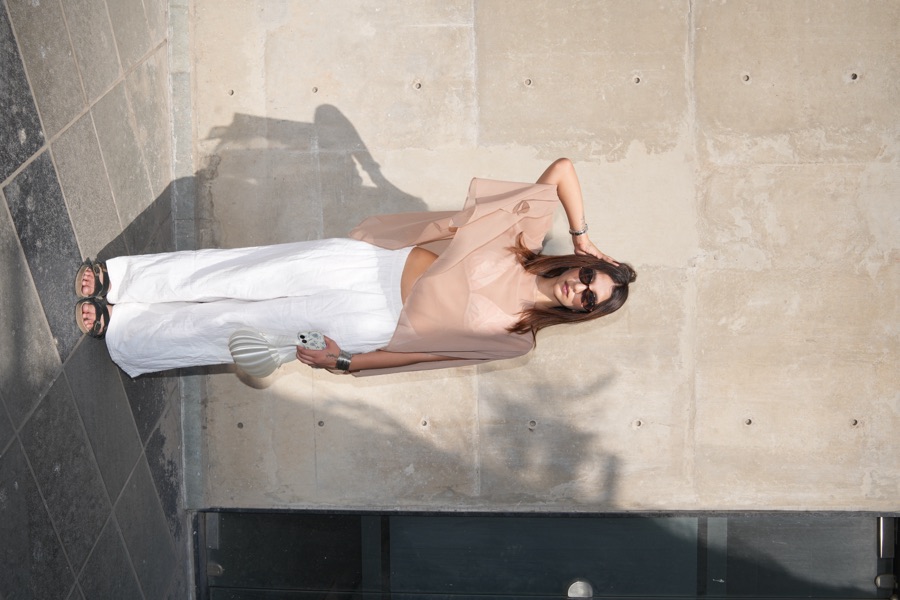 Street style look — peach chiffon top with white trousers in sunlight