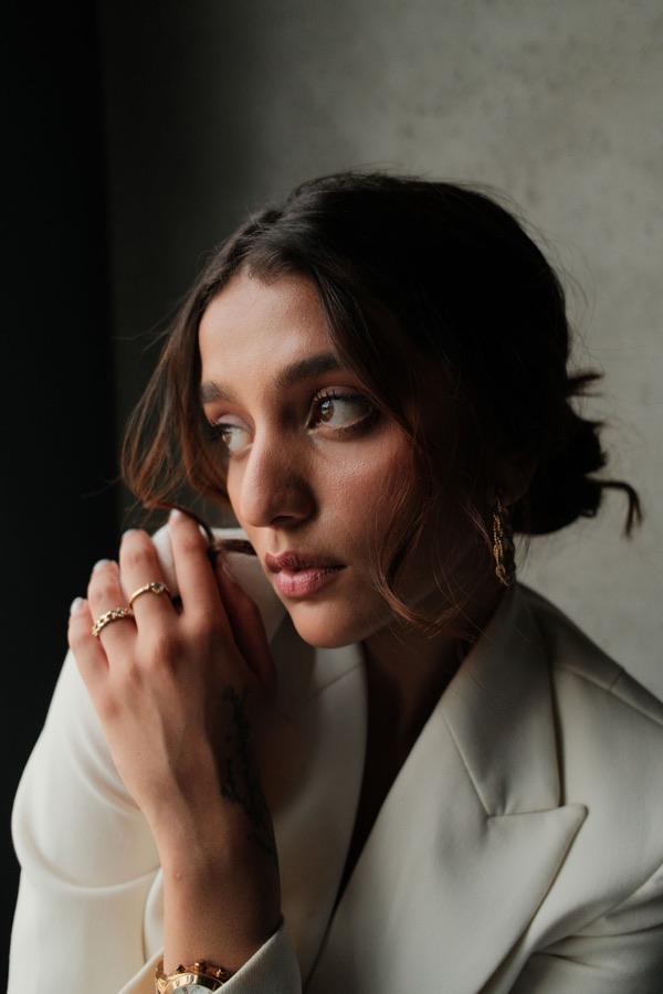 Contemplative portrait with gold rings, hand raised to her lips