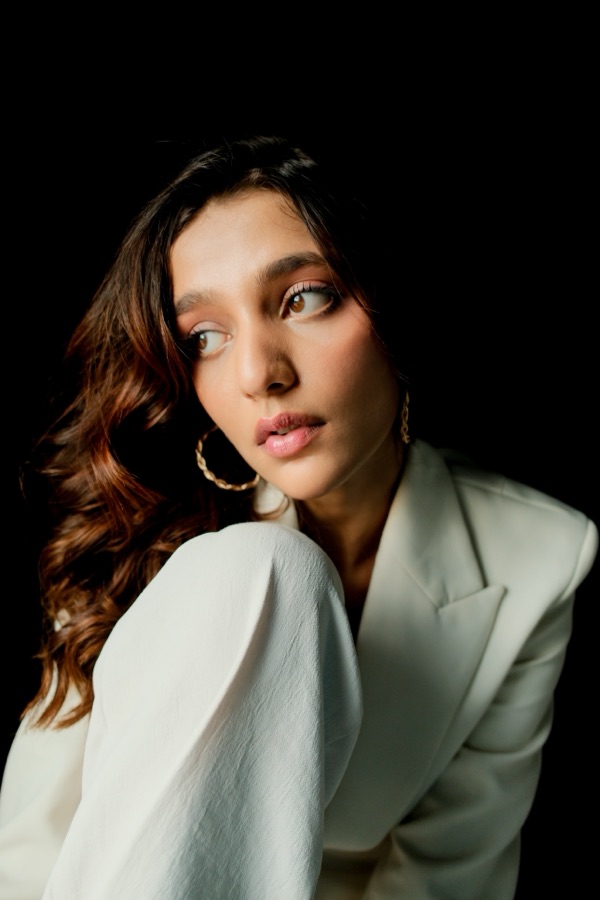 Portrait in a white blazer with hoop earrings, gazing left