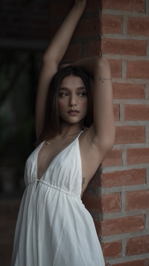 Video still — leaning against a brick column with arms raised