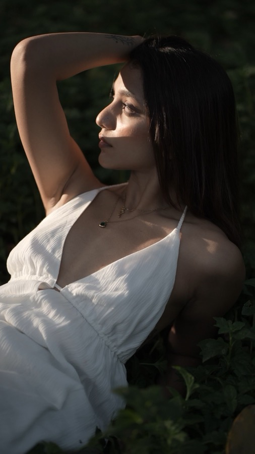 Video still — lying back in a meadow in a white dress, evening light